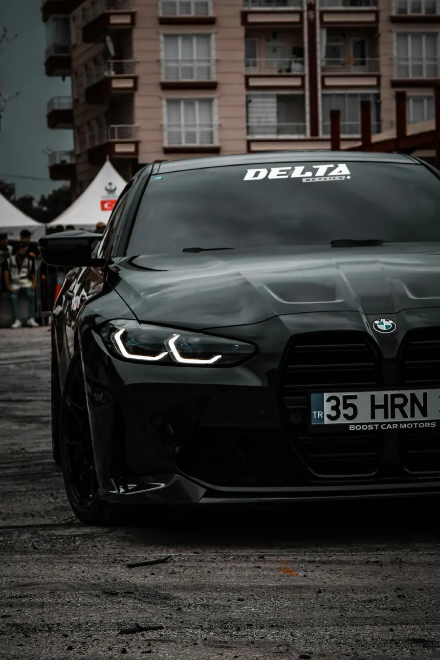 Front view of a black BMW with custom headlights in an urban setting.